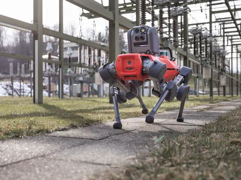 A four-legged inspection robot walking along a path inside an electrical substation